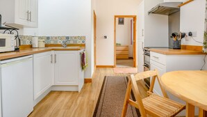 Une cuisine moderne avec des armoires blanches, un plan de travail en bois, un puits de lumière et une vue sur une chambre.