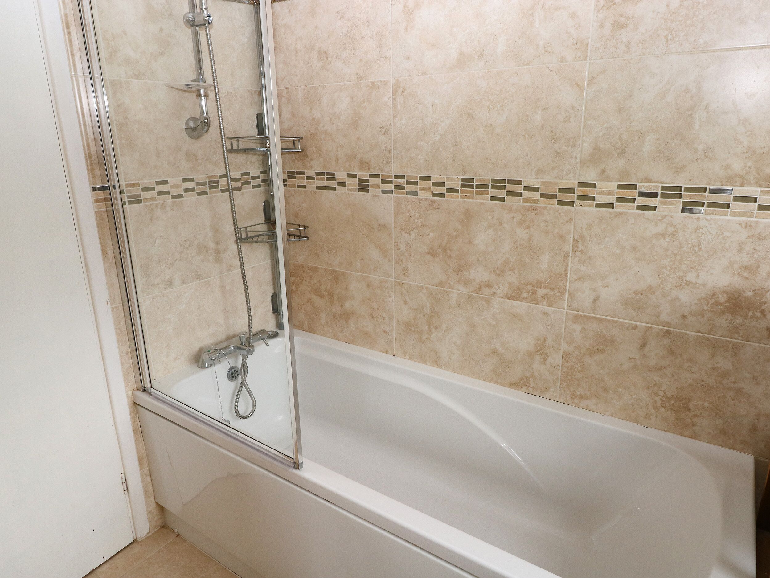 Une salle de bain avec une baignoire, une douche et un mur carrelé.