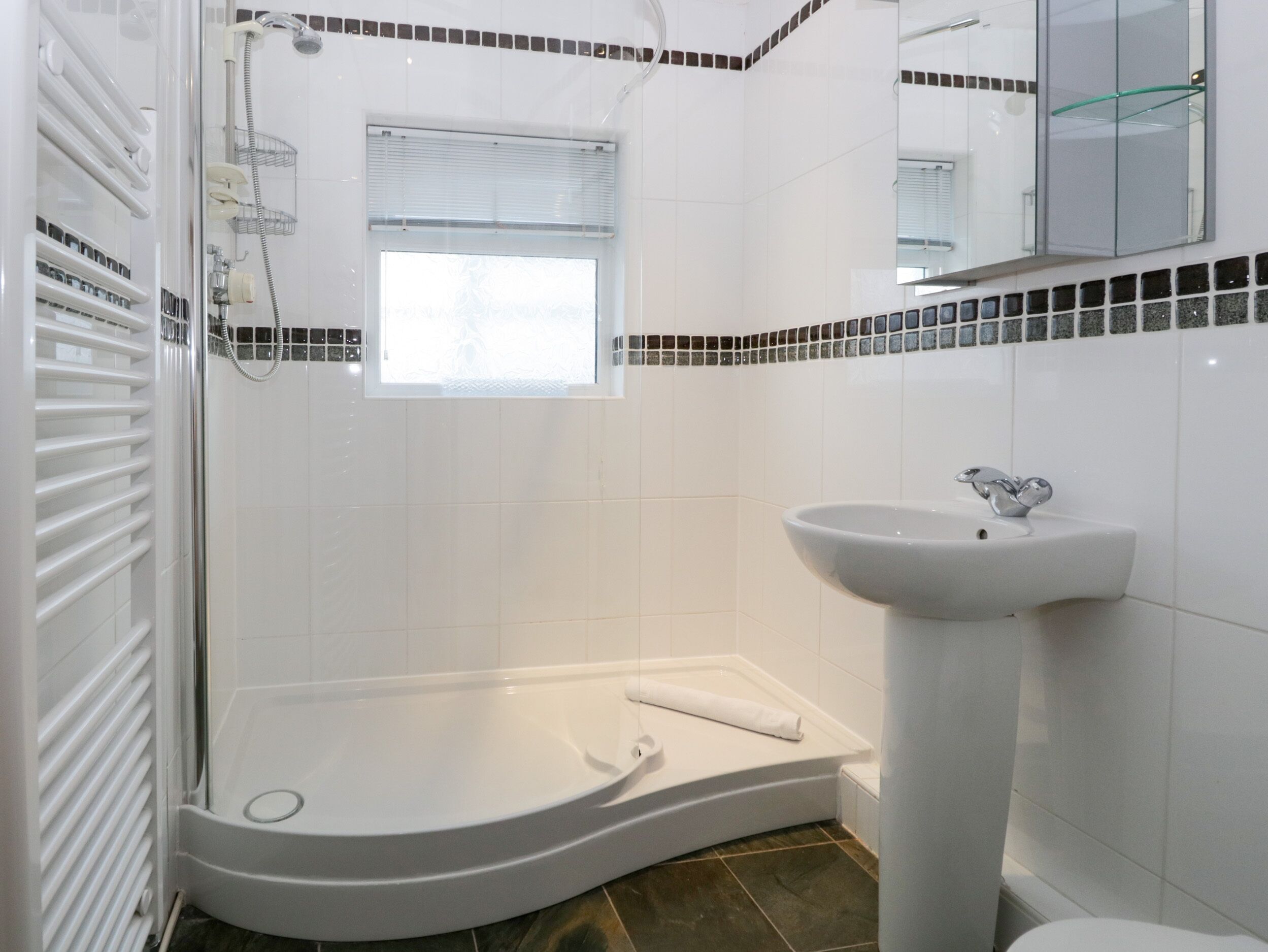 A modern bathroom with a curved bathtub, a pedestal sink, and a shower area.