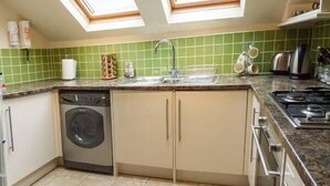 A compact kitchen with a dishwasher, sink, and stove. - Bluebird Loft (Coniston)