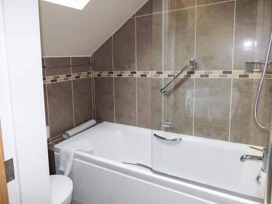 Un baño moderno con ducha envuelta en vidrio, una bañera blanca y un inodoro.