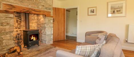 A cozy living room with a stone fireplace, a sofa, and a framed landscape painting.
