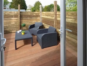 Enjoy an outdoor space with a table, chair, and potted plant, surrounded by a wooden fence and glass door.