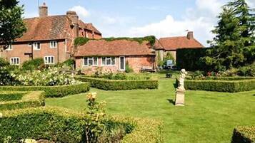 Traditional brick house with a beautifully landscaped garden featuring a central statue and evenly spaced windows.