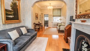 A living room with a grey sofa, a white rug, a fireplace, and a dining area with a table and chairs. - 12 Deva Terrace (Chester)