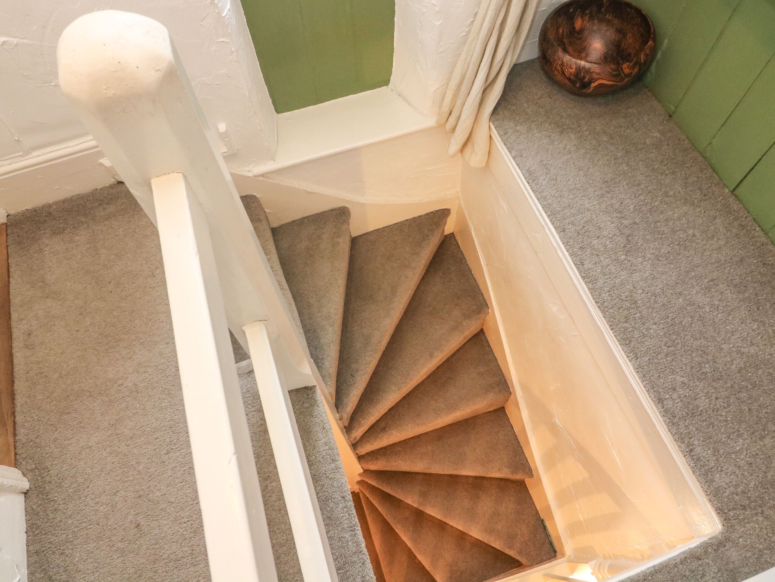 Een trap met een bekleed plateau en een groene wand.