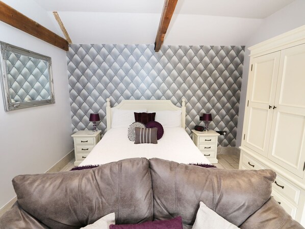 A bedroom with a bed, two bedside tables, a wardrobe, and a mirror.