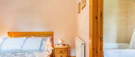 A bedroom with a wooden bed, a nightstand, a lamp, and a radiator.