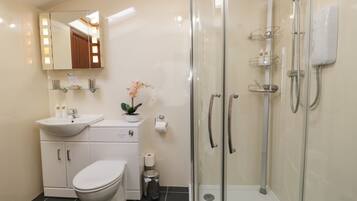 A modern bathroom with a toilet, sink, and glass-enclosed shower.