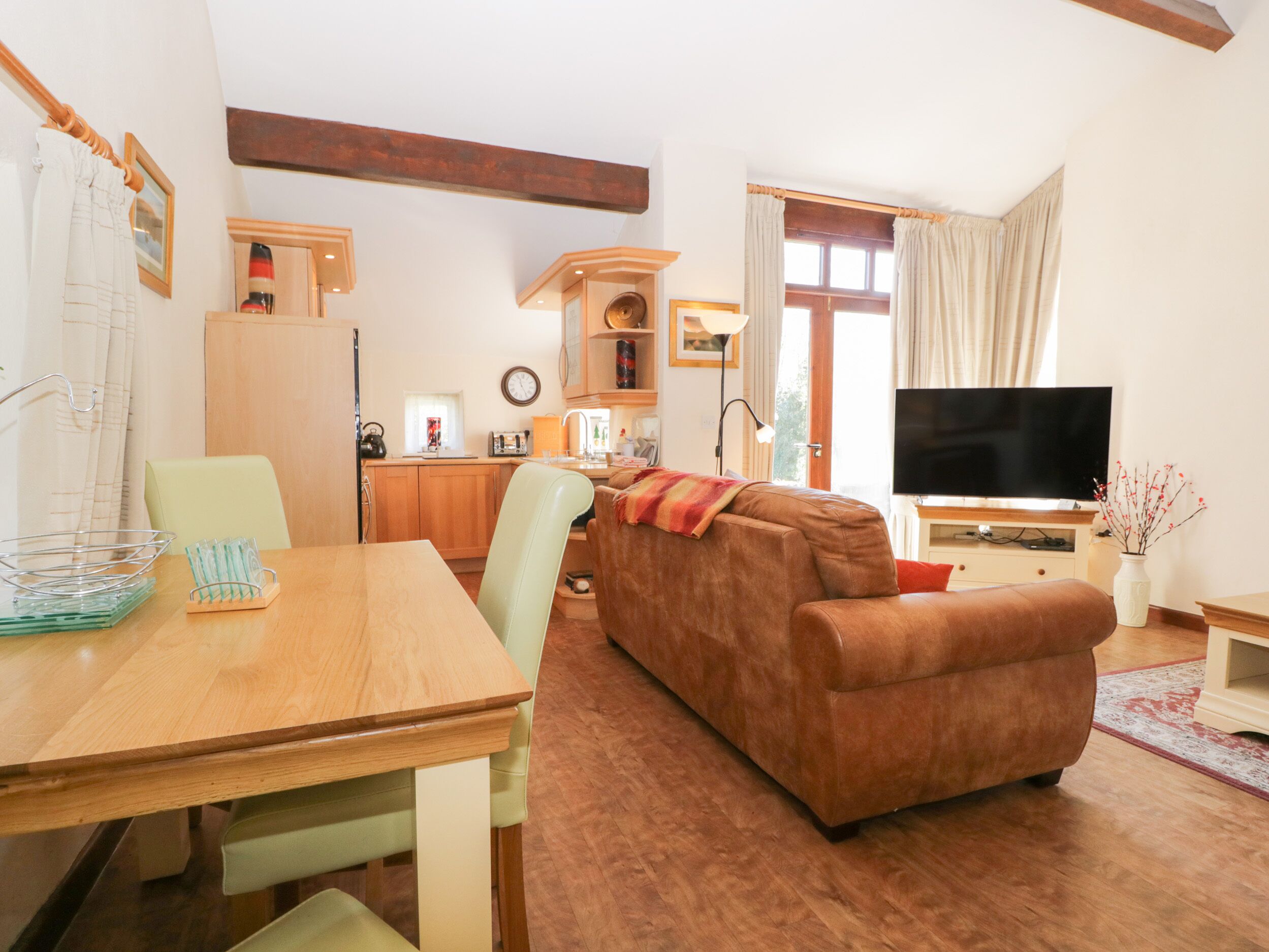 A cozy living room with a sofa, a TV, and a dining area with a table and chairs.