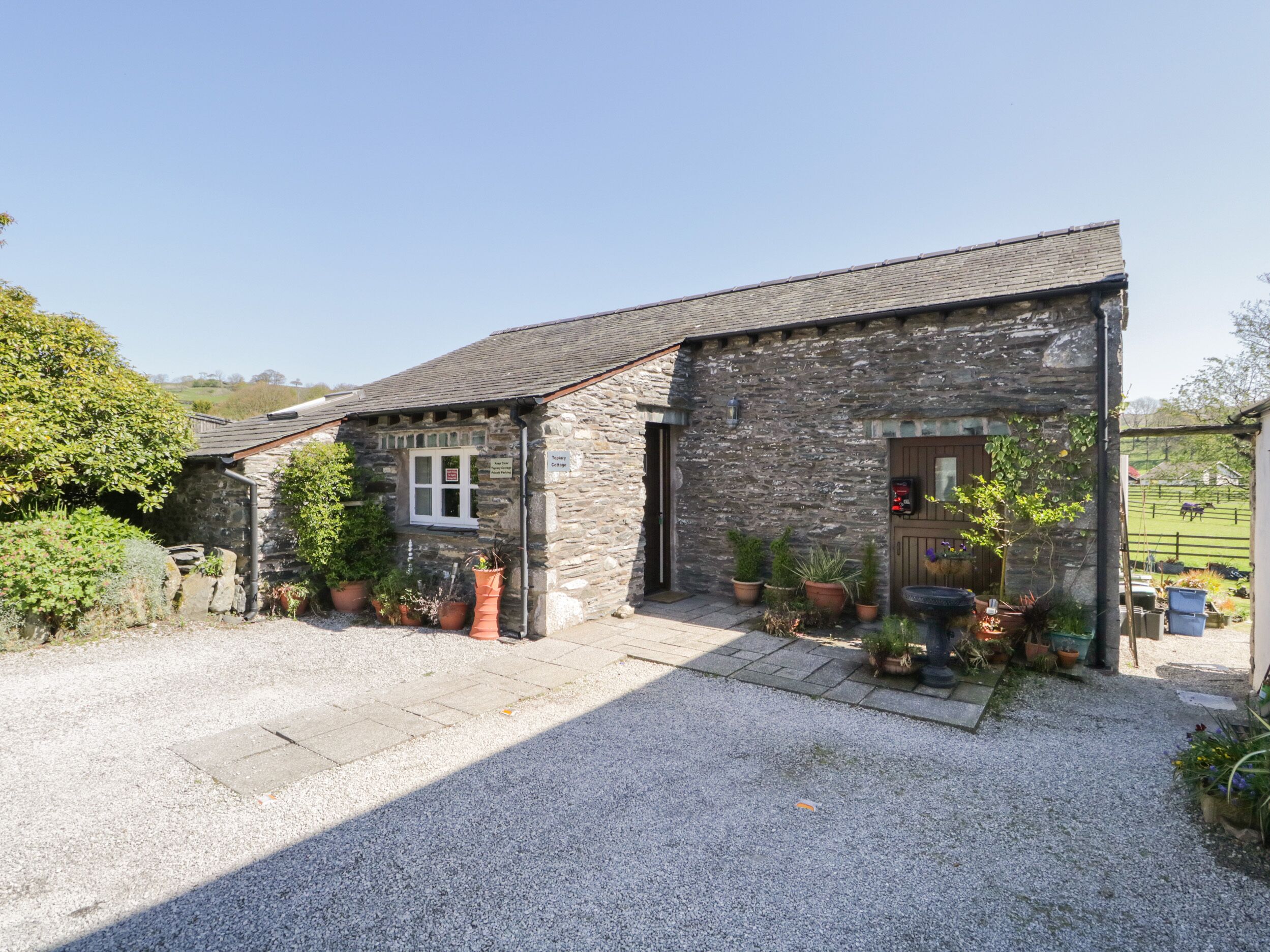 A stone building with a gravel driveway and potted plants.
