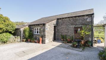 A stone building with a gravel driveway and potted plants.
