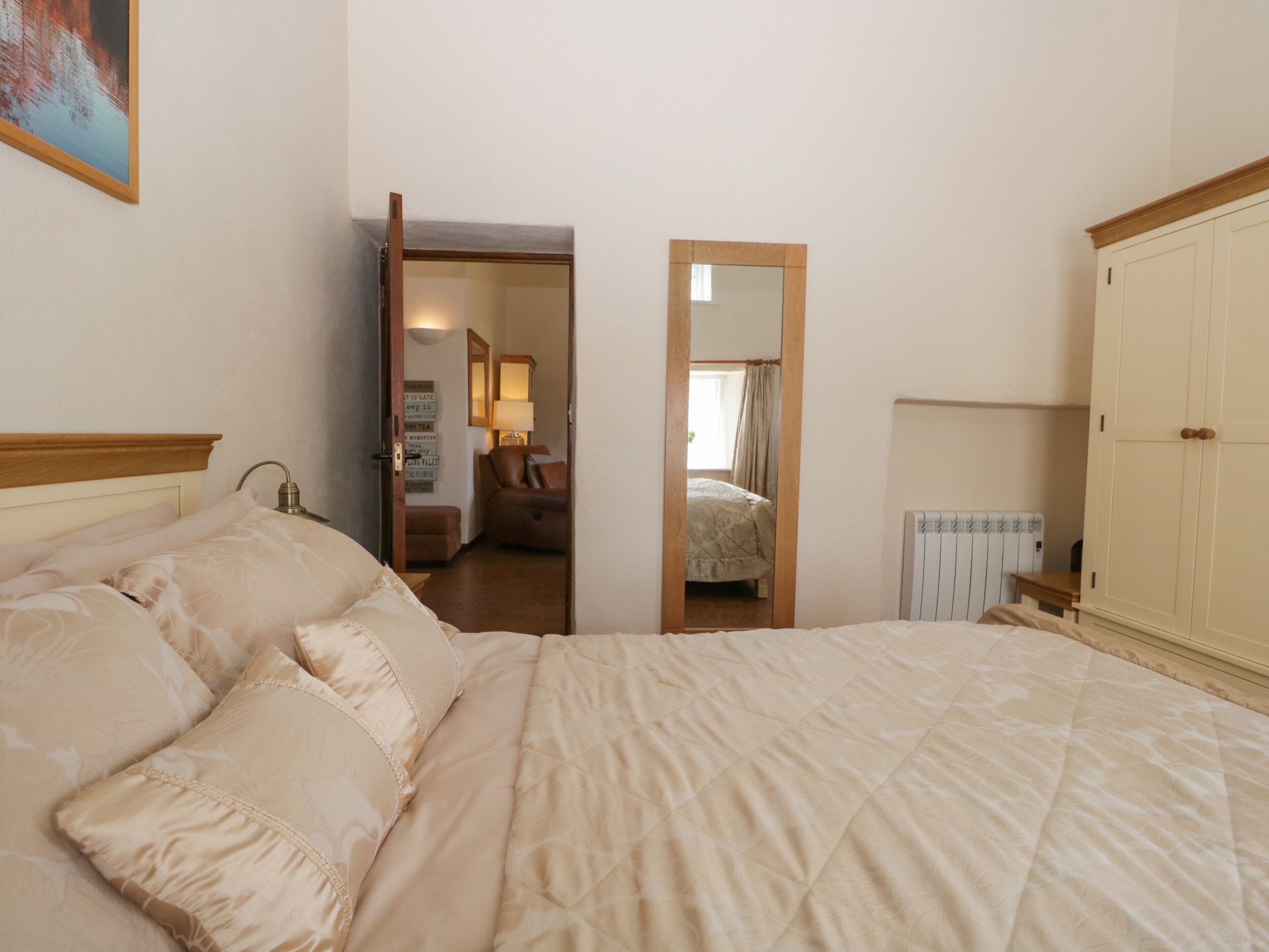 A bedroom with a large bed, a wardrobe, a radiator, and a mirror.
