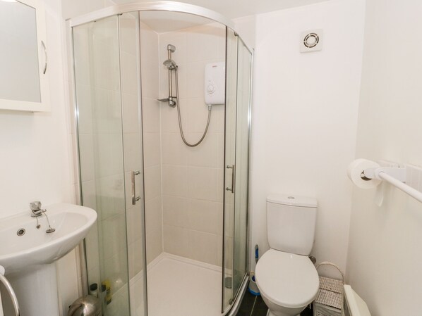 Een moderne badkamer met een douchecabine van glas, een wit wastafelmeubel en een toilet.