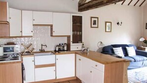 A compact kitchen with white cabinets, a wooden countertop, a microwave, and a stove. - Cider Barn Cottage (Tewkesbury)