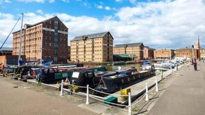 A canal-side area with boats docked, buildings with multiple windows, and a clear sky. - Cider Barn Cottage (Tewkesbury)