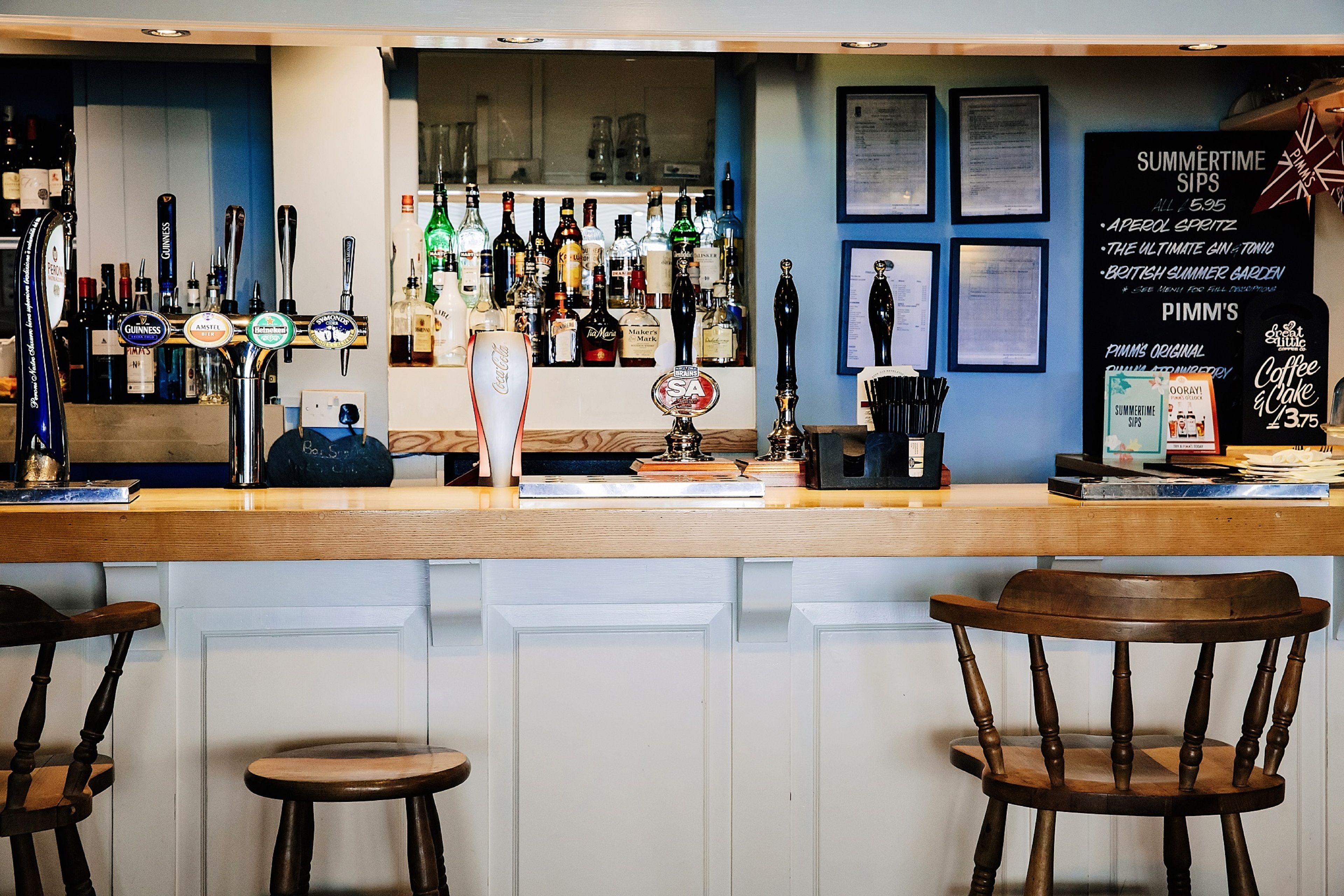 Een bar met verschillende tappunten, een toonbank en krukken.