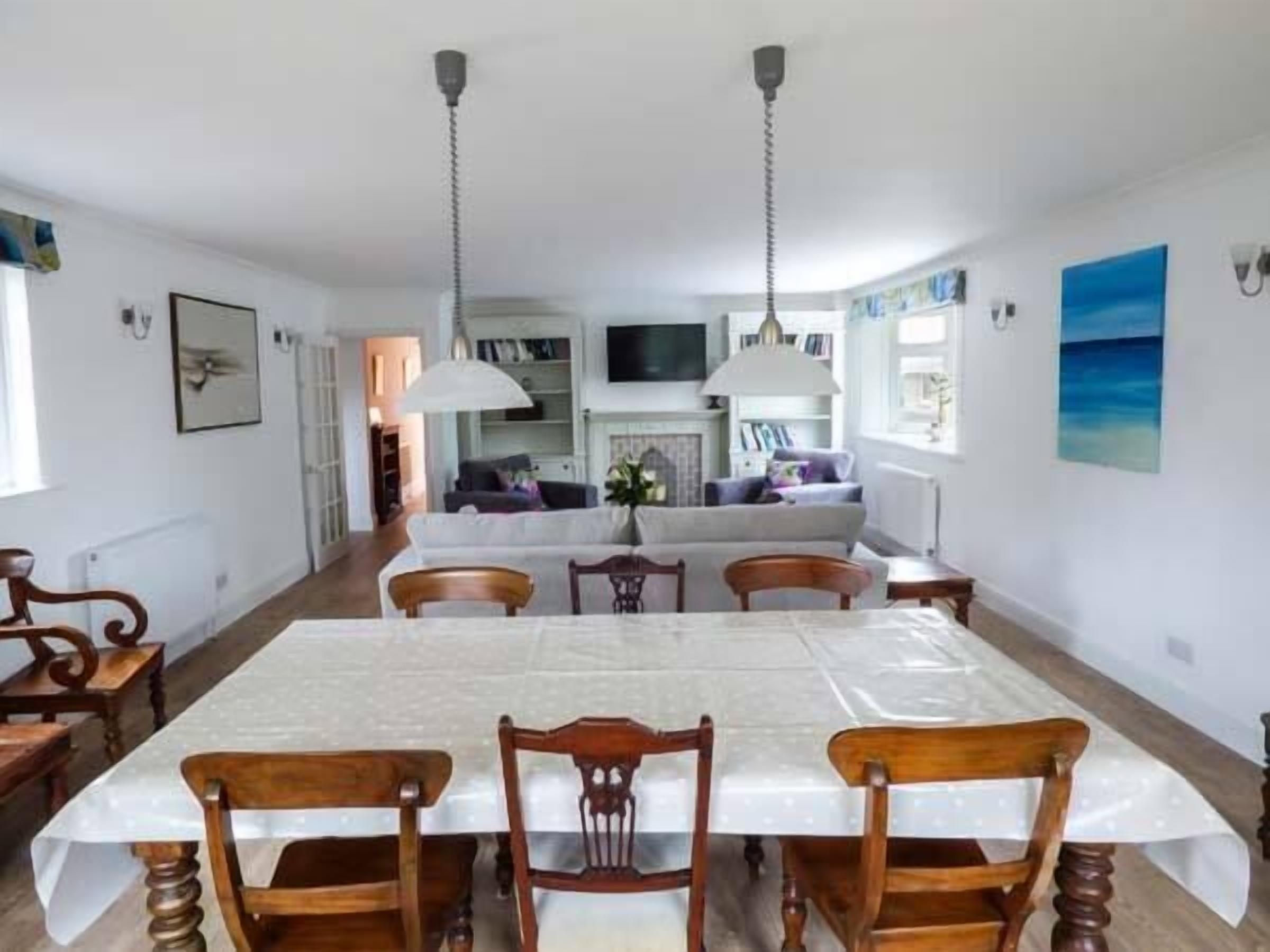 A dining area with a table set for four, surrounded by wooden chairs. There are two pendant lights above the table.