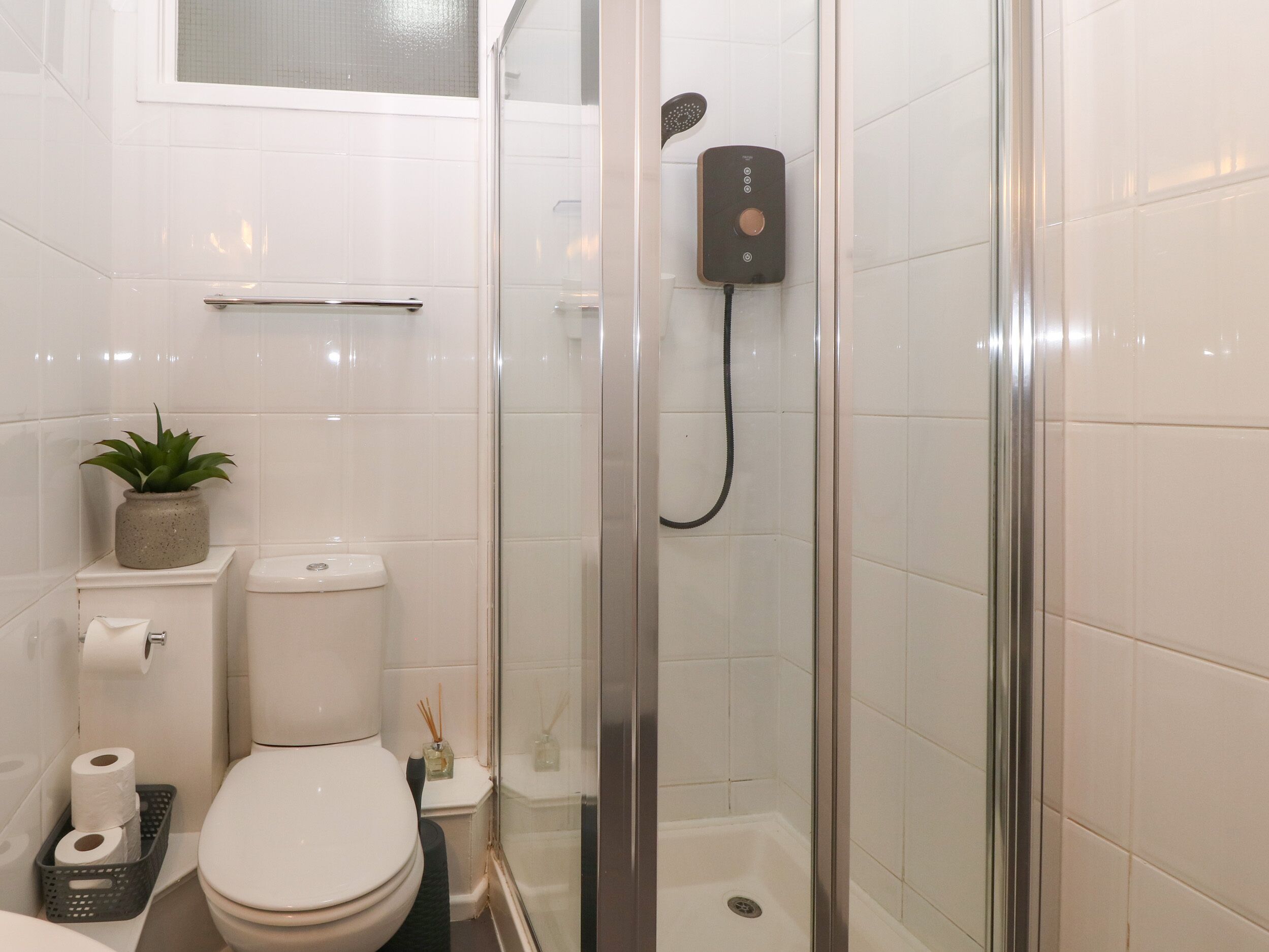 A modern bathroom with a glass-enclosed shower, a toilet, and a sink.