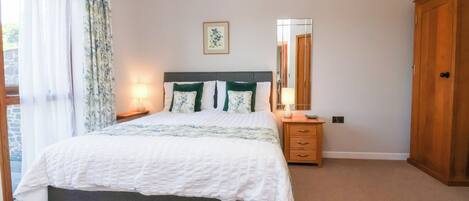 A bedroom with a bed, a nightstand, a dresser, a mirror, and a door.