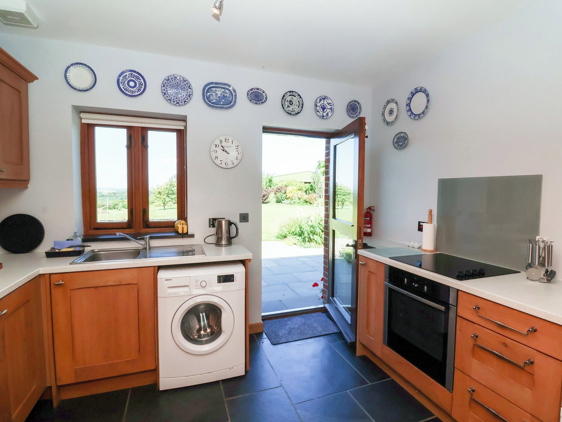 A compact kitchen with a washing machine, a sink, a stove, and a window.