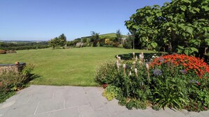 A spacious lawn with a stone pathway leading to a house. - Pound Cottage (Torrington)