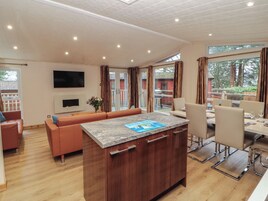 Una cocina moderna con una isla central, armarios de madera y un comedor con mesa y sillas.