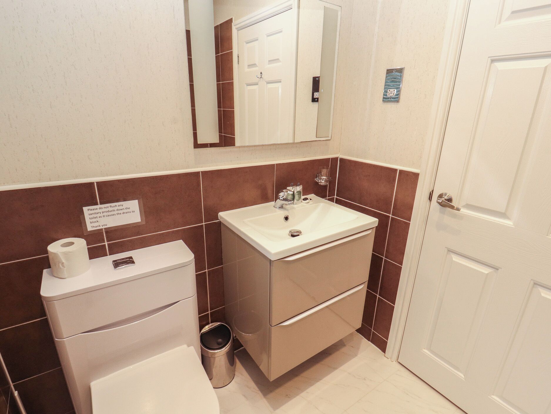 Une salle de bain avec des toilettes, un lavabo et une poubelle.