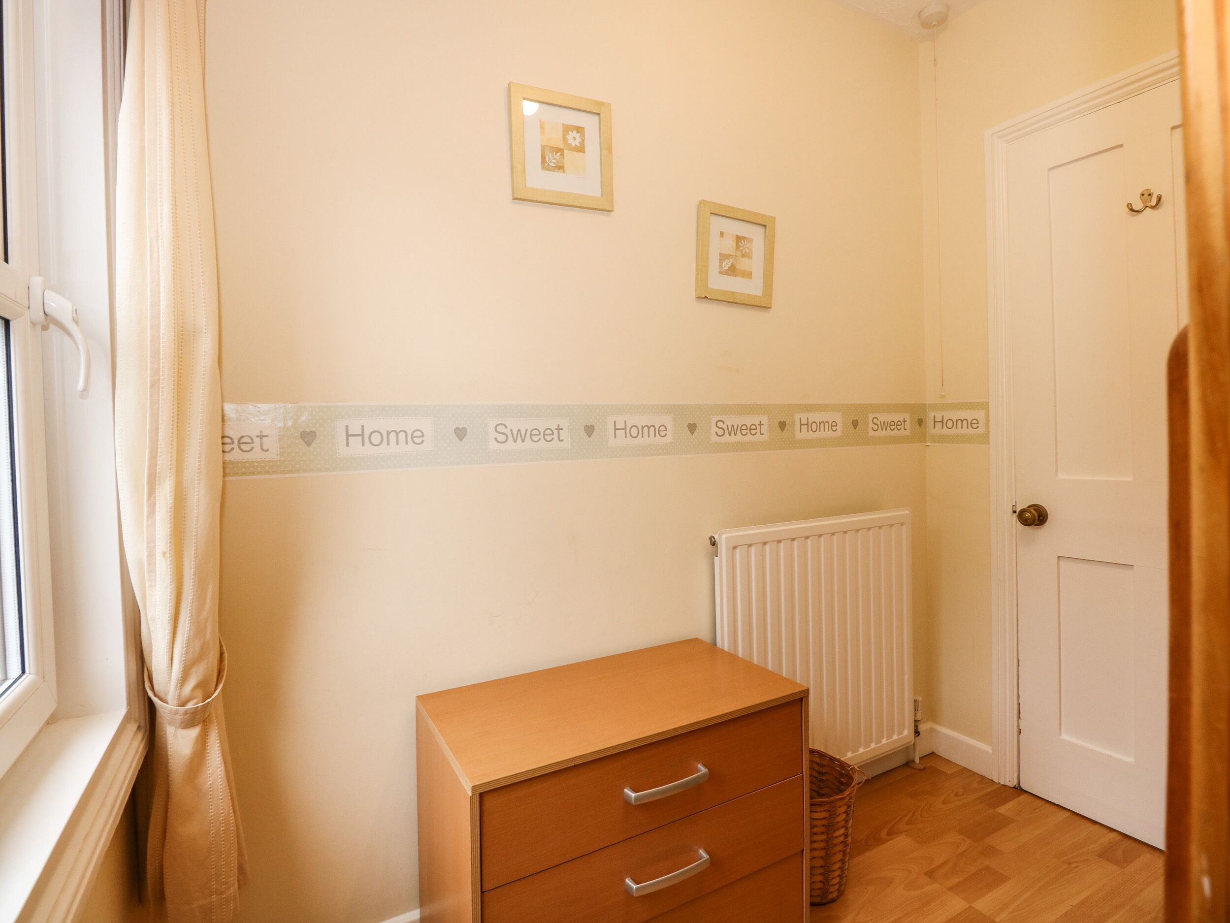 A room with a radiator, a door, and a small wooden cabinet.