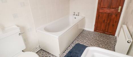 A bathroom with a white bathtub, a toilet, and a shower.