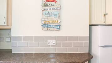 A kitchen with a countertop, cabinets, and a wall-mounted sign with seafood-related words.