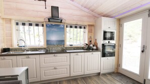 A kitchen with white cabinets, a built-in oven, and a window with blinds. - Old Joiners Shop (Saltburn-by-the-Sea)