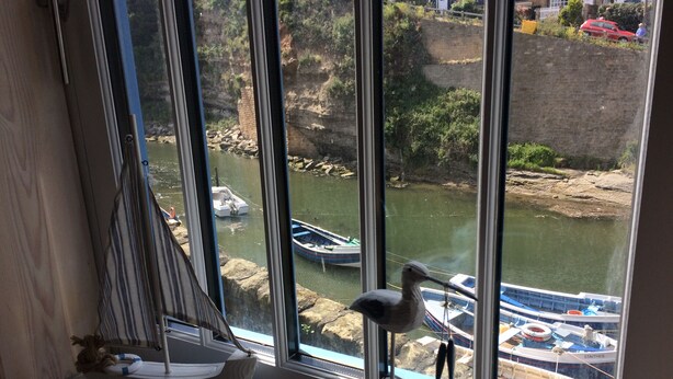 A view of a river with boats, a sailboat model, and a bird figurine on a windowsill. - Old Joiners Shop (Saltburn-by-the-Sea)