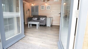 A room with a grey sofa, a small table, and a cabinet. There are wooden walls and a ceiling with a light fixture. - Old Joiners Shop (Saltburn-by-the-Sea)
