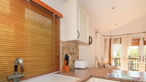 A kitchen with a double sink, wooden blinds, a toaster, and a view of the outdoors. - Harvester Lodge (Weston-super-Mare)