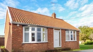 A single-story brick house with a tiled roof, white-framed windows, and a chimney. - Glenhaven (Saxmundham)