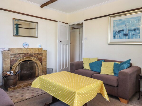 A living room with a fireplace, a sofa, a table with a yellow polka dot tablecloth, and a framed painting on the wall. - Highdown (Kingsbridge)