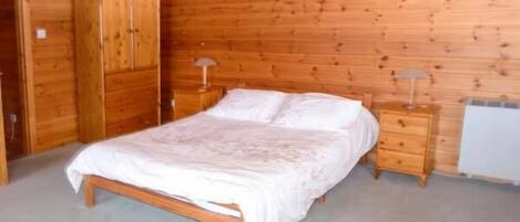 A wooden-paneled bedroom with a bed, nightstands, and a wardrobe.