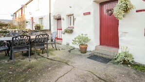A white building with a red door and a sign reading "Stable End". - Stable End Cottage (Seascale)
