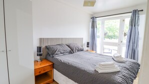 Et soveværelse med seng, sengeborde, en lampe og udsigt til det fri.