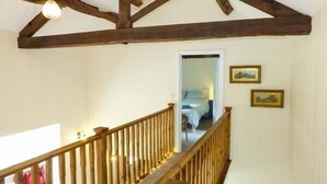 Un escalier en bois avec une rampe, un ventilateur de plafond et une porte donnant sur une chambre à coucher.