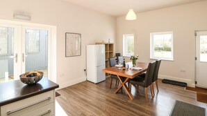 Une cuisine moderne avec une table à manger en bois, des chaises et un réfrigérateur blanc.