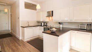 Une cuisine moderne avec des meubles blancs, un îlot central et un four encastré.