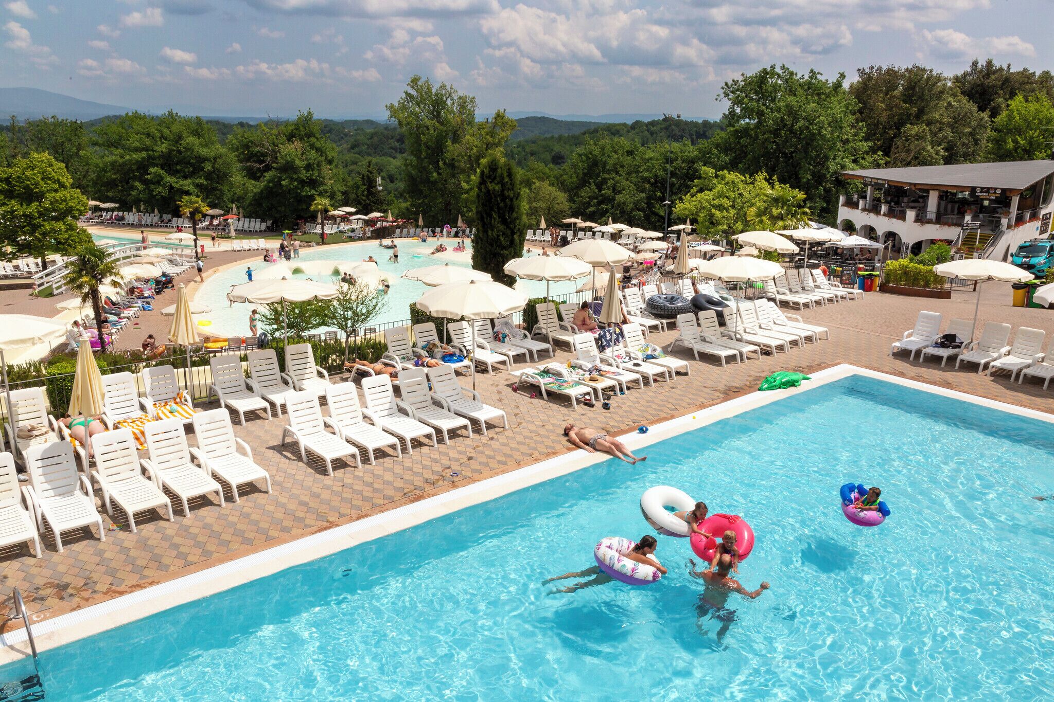 A pool area with lounge chairs, umbrellas, and a view of the surrounding landscape.