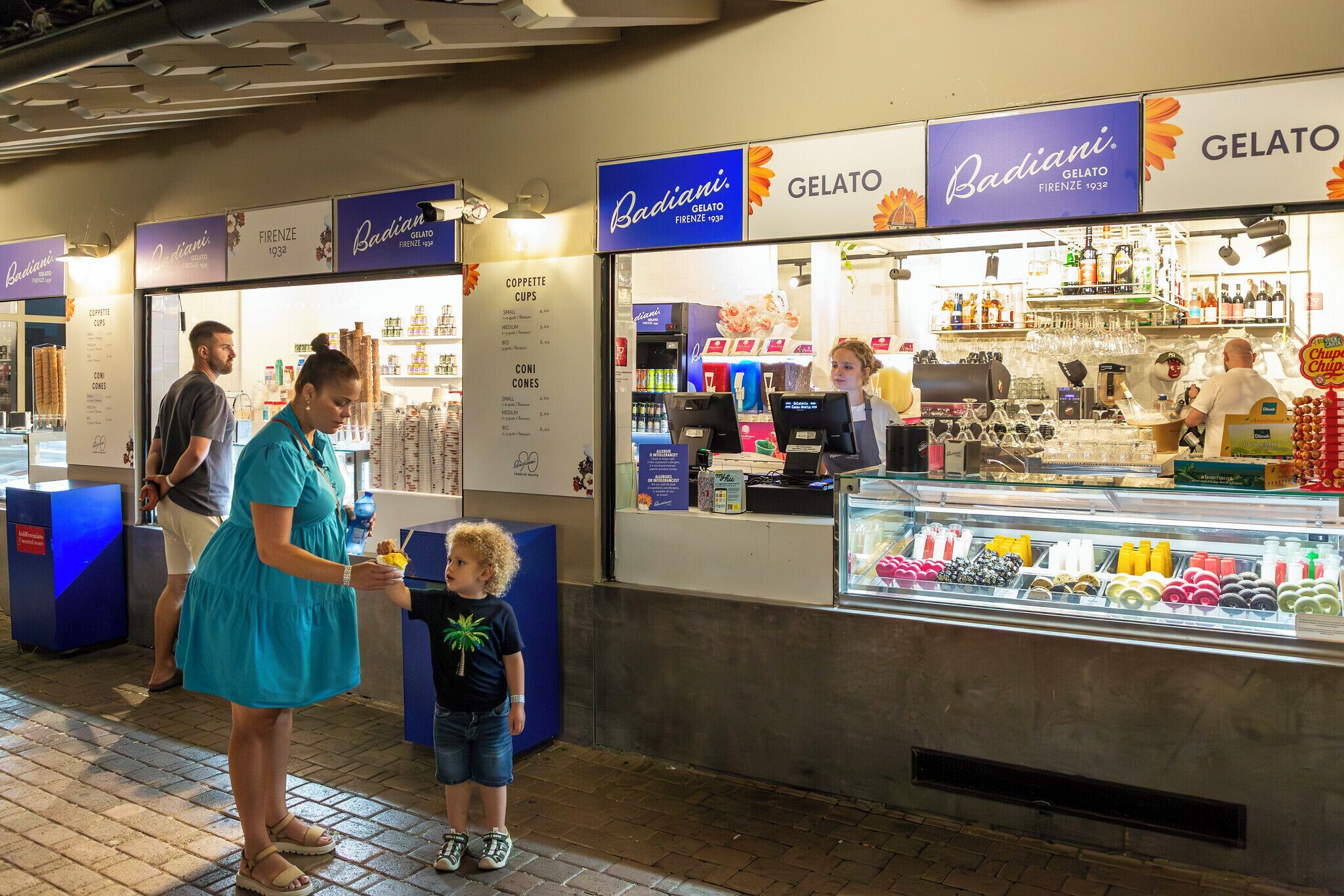 A gelato stand with a menu board and a display case of gelato flavors.