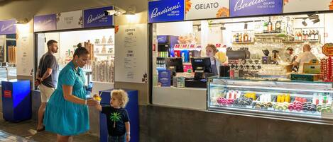 A gelato stand with a menu board and a display case of gelato flavors.