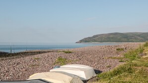 A rocky beach with boats and a clear view of the sea and hills in the background. - 3 Old Police Station (Minehead)