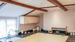 A kitchen with white cabinets, a black countertop, and wooden beams on the ceiling. - 3 Old Police Station (Minehead)