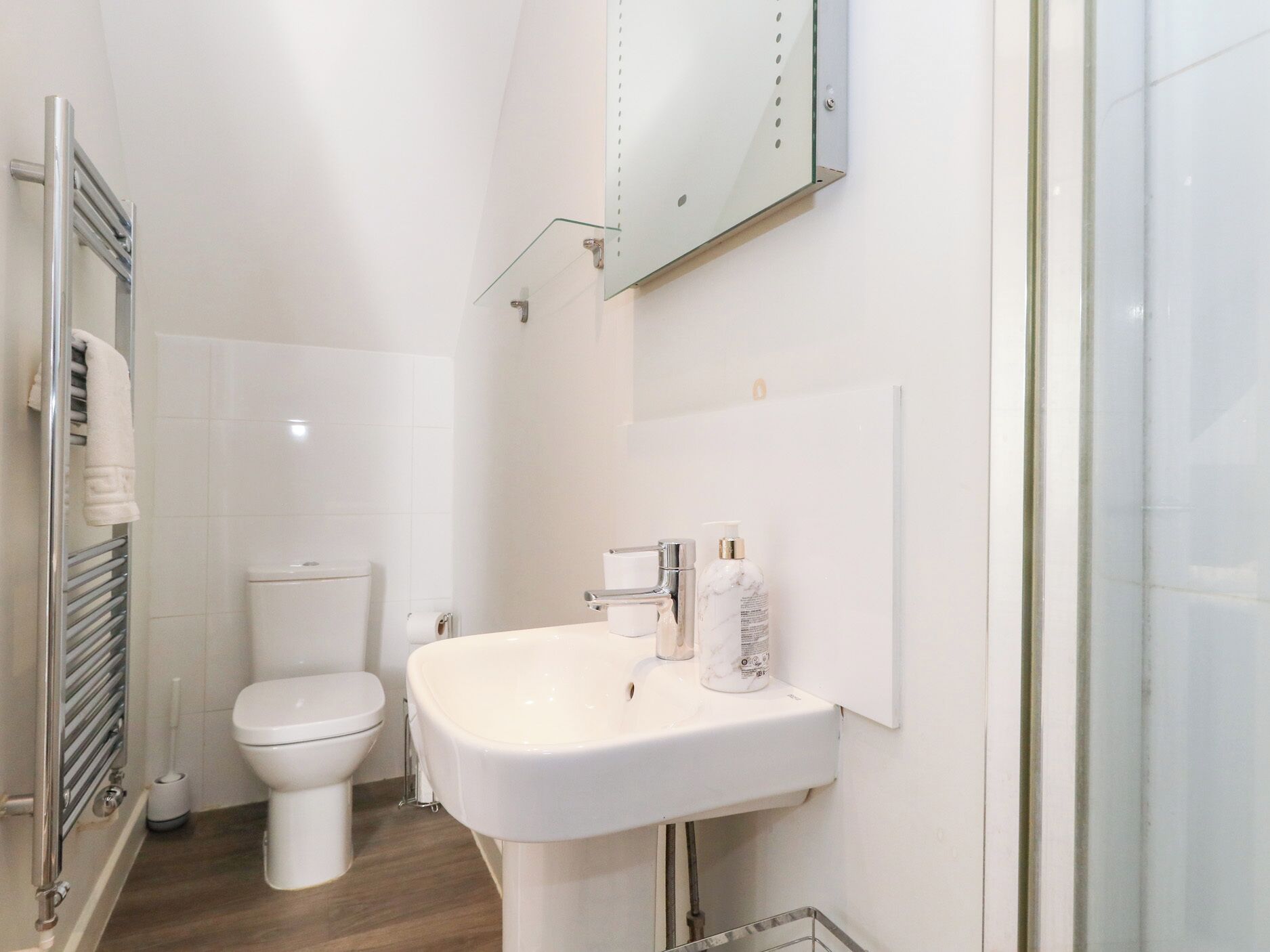 Ein modernes Badezimmer mit Waschbecken, Toilette und Duschbereich in Weiß.