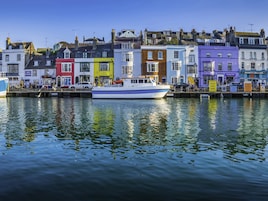 Un muelle con un barco amarrado, rodeado de edificios coloridos y diversas tiendas con rótulos.